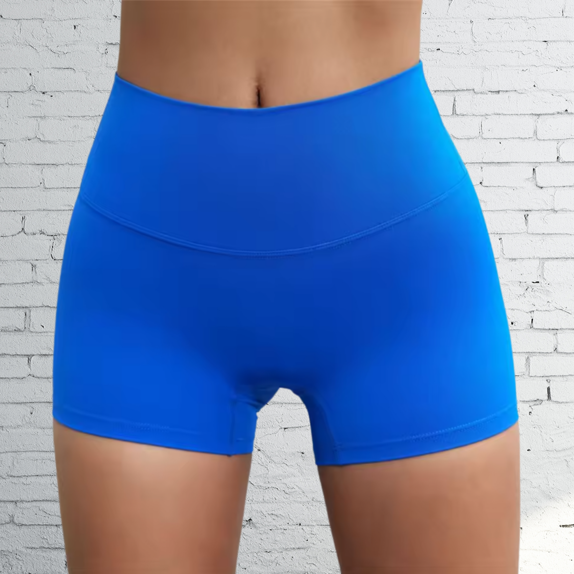 Blue athletic shorts worn by a person against a white brick wall background
