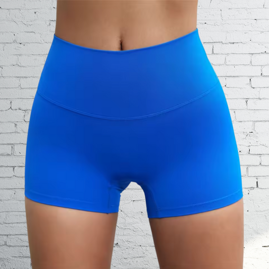 Blue athletic shorts worn by a person against a white brick wall background