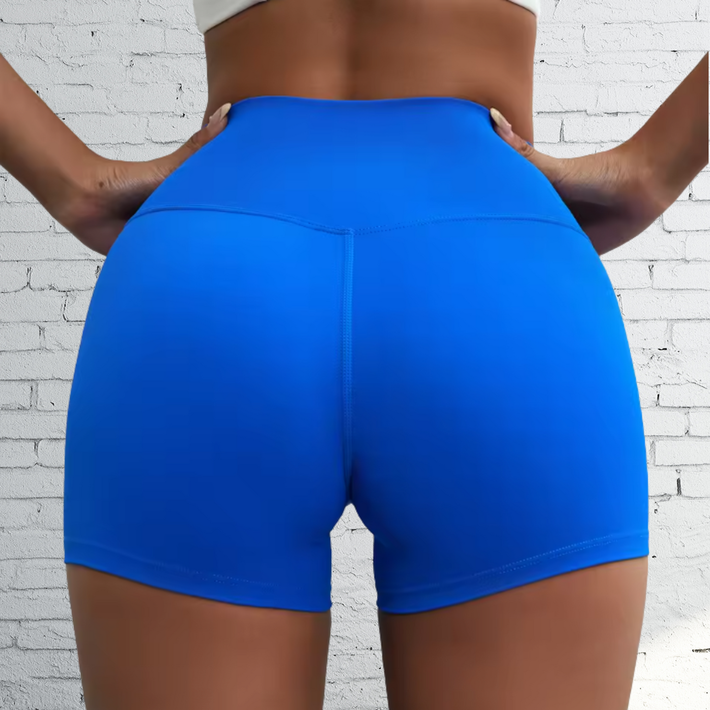 Blue athletic shorts worn by a person against a white brick wall.