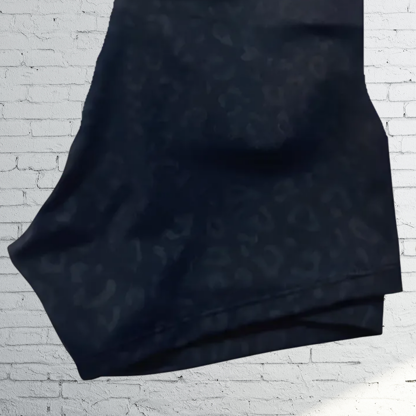 Black fabric with a subtle pattern on a white brick wall background
