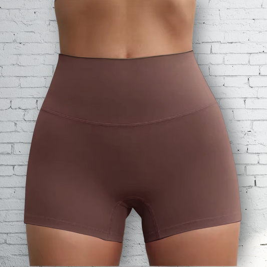 Brown shorts worn by a person against a white brick wall background